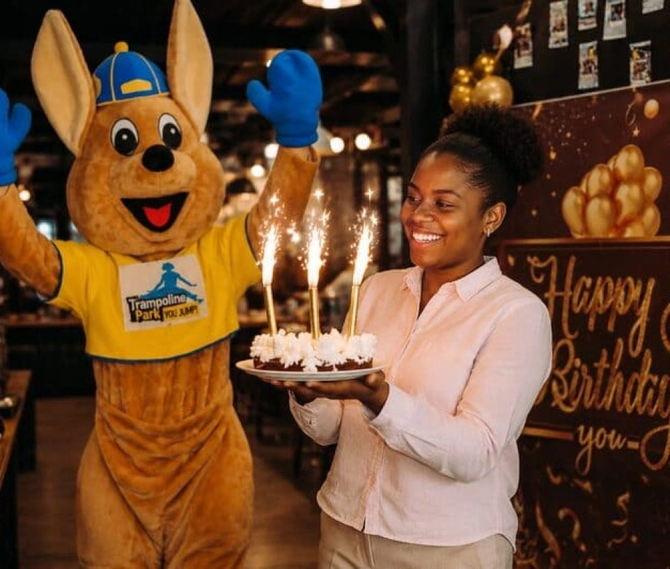 une animatrice amène le gateau d'anniversaire avec la mascotte jumpy
