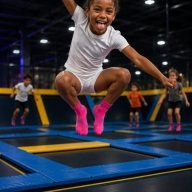 fille saute sur un trampoline et tire la langue dans un parc de jeux intérieur avec trampoline
