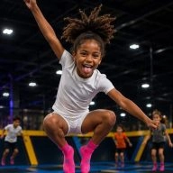 fille saute sur un trampoline et tire la langue dans un parc de jeux intérieur avec trampoline
