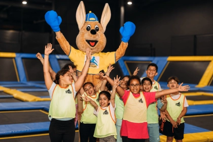 groupes enfants levant les bras avec mascotte parc de jeux interieur