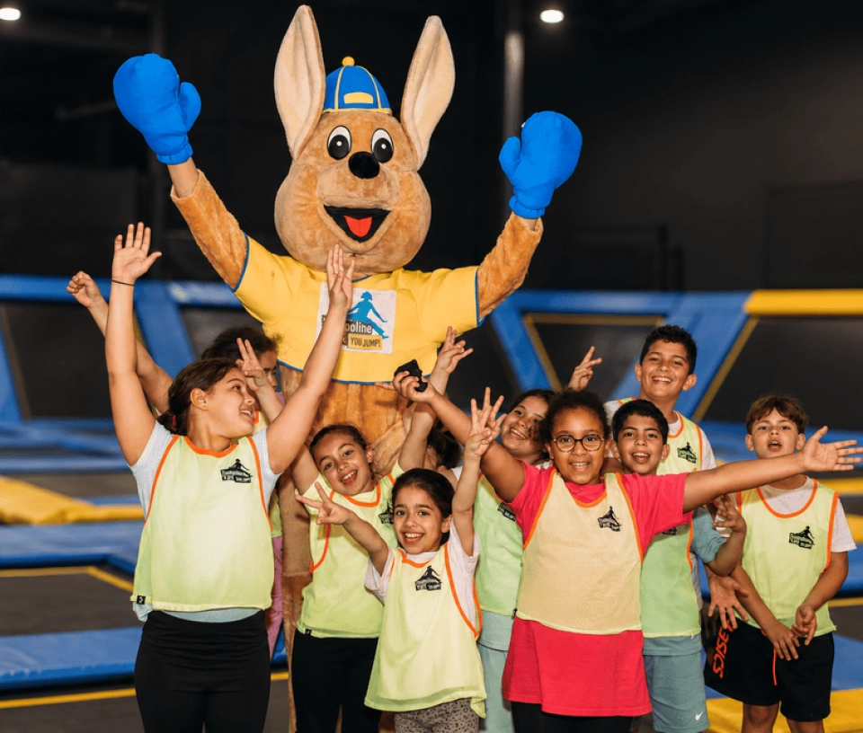 groupes enfants levant les bras avec mascotte parc de jeux interieur