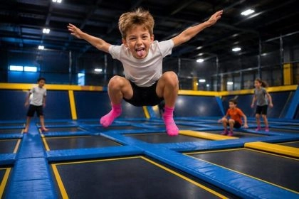 un petit garçon saute dans les airs et fait une grimace en faisant l'avion sur un trampoline park you jump
